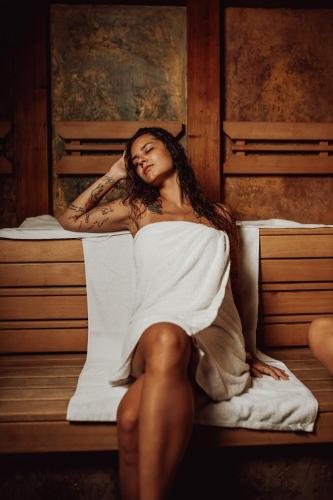 a woman sitting on top of a bed at Hotel Kotarz Spa&Wellness in Brenna