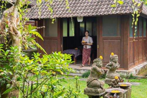a woman standing outside of a house with statues at Pertiwi Resort & Spa in Ubud