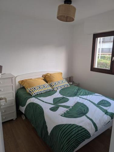 - une chambre dotée d'un lit avec une couverture verte et blanche dans l'établissement Appartement à 2 min de la plage !, à Villers-sur-Mer