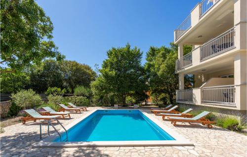 a swimming pool with lounge chairs and a building at 2 Bedroom Nice Apartment In Pinezici in Pinezici