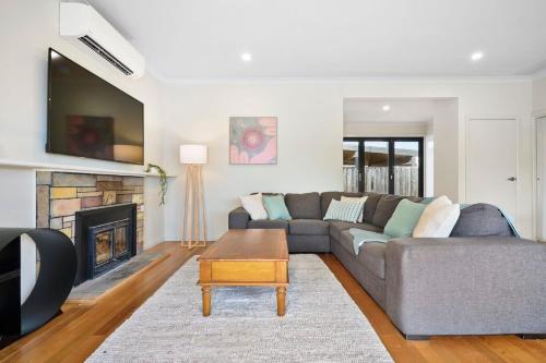 a living room with a couch and a fireplace at 4 Bedroom Home in Heathmont Perfect for Families in Heathmont