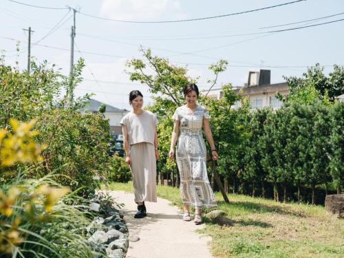 two women walking down a path in a garden at RITA Yame Fukushima in Yame