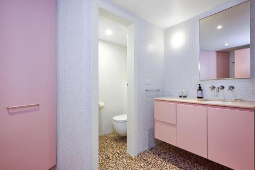 a white bathroom with a toilet and a sink at Bourke Street Urban Retreat in Melbourne