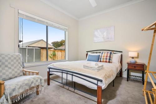 a bedroom with a bed and a chair and a window at 4 Bedroom Home in Heathmont Perfect for Families in Heathmont