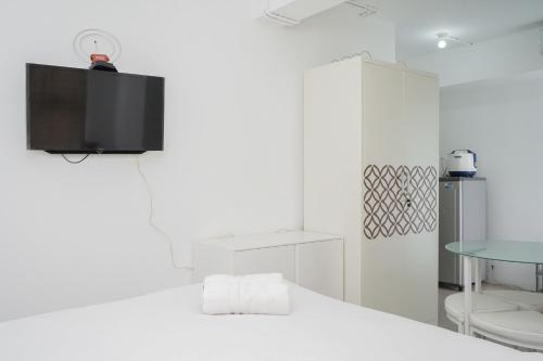 a white room with a tv on the wall at New and Simply Studio at Urbantown Serpong Apartment By Travelio in Tangerang
