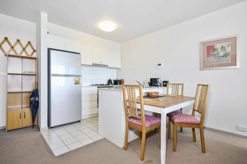 a kitchen with a table and chairs and a refrigerator at The Gallop Kensington in Melbourne
