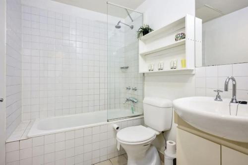 a white bathroom with a toilet and a sink at The Gallop Kensington in Melbourne