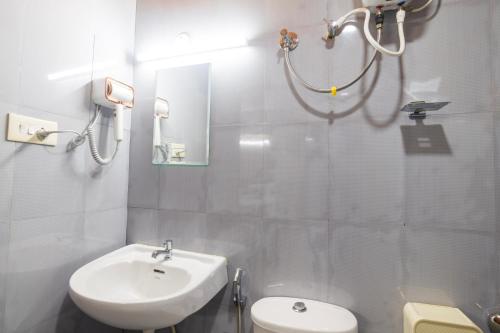 a white bathroom with a sink and a toilet at Sancta Maria in Nedumbassery