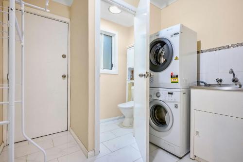 a bathroom with a washer and dryer next to a toilet at Spacious 3BR Family Haven in Upper Ferntree Gully in Fern Tree Gully