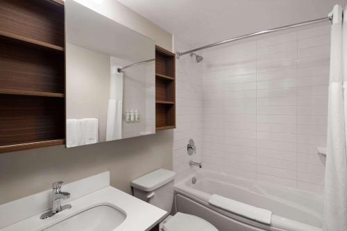 a bathroom with a sink and a toilet and a tub at Microtel Inn & Suites by Wyndham Kirkland Lake in Kirkland Lake