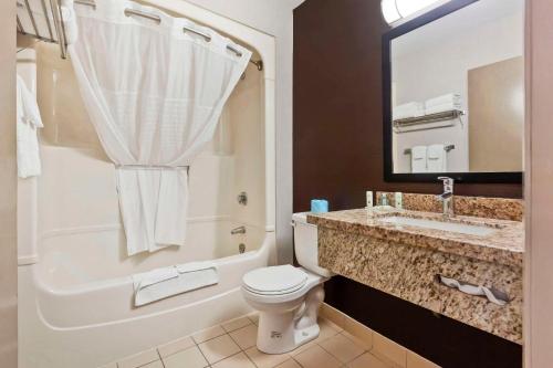 a bathroom with a toilet and a sink and a tub at Quality Inn in Peterborough