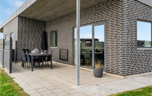 Un patio con una mesa y sillas en una pared de ladrillos. en Holiday Home Ringkøbing 57, en Søndervig