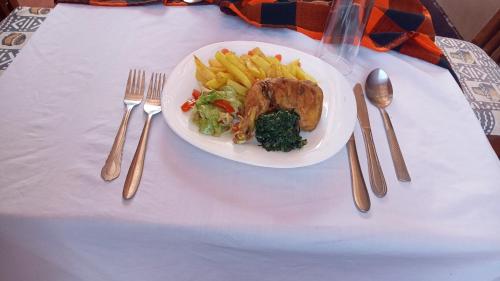 Een bord met vlees en friet op een tafel met bestek. bij Hillsgate Homes Lodge in Namanga in Namanga