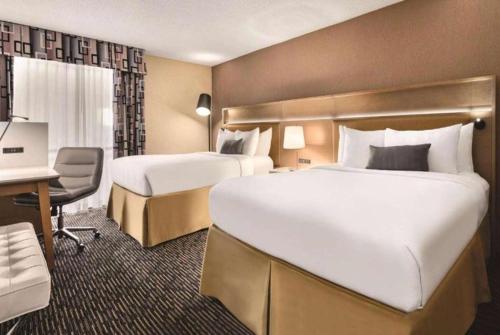 a hotel room with two beds and a desk at Wyndham Garden Conference Center Champaign - Urbana in Champaign
