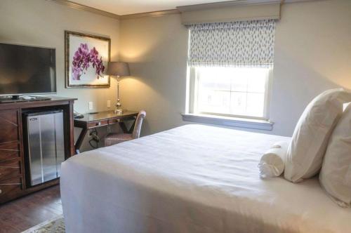 a bedroom with a white bed and a television at The Bolling Wilson Hotel in Wytheville