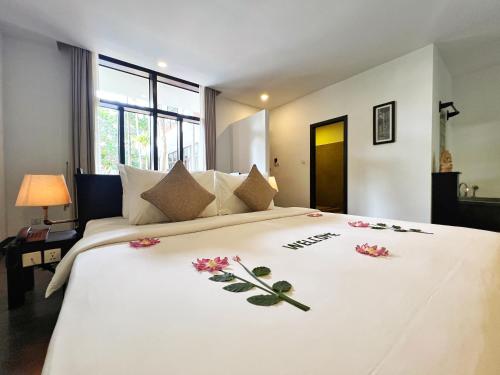 a bedroom with a large white bed with flowers on it at The Bliss Angkor in Siem Reap