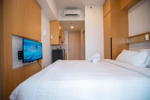 a bedroom with a white bed and a flat screen tv at Tokyo Riverside Apartment @ PIK 2 in Tangerang