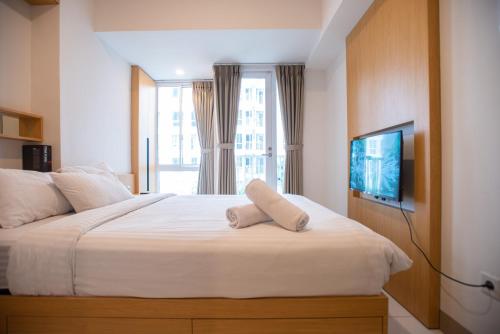a bedroom with a bed with a television and a window at Tokyo Riverside Apartment @ PIK 2 in Tangerang