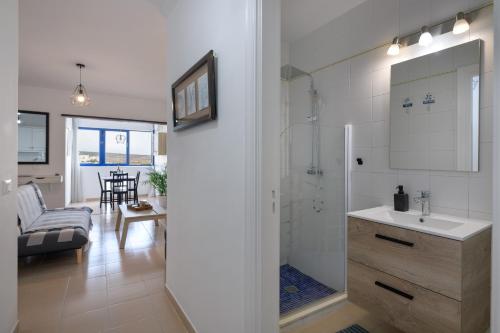 a bathroom with a sink and a shower and a living room at Costa Jameos Oceanfront-Lava Pools in Punta Mujeres