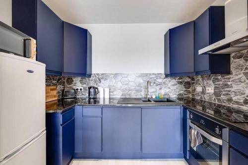 a kitchen with blue cabinets and a white refrigerator at Large 2 Bed 2 Bath Central Manchester in Manchester