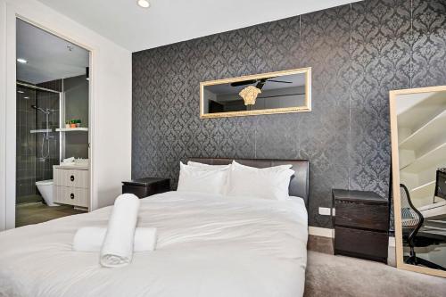 a bedroom with a white bed and a bathroom at Riviera Edgewater Maribyrnong in Melbourne