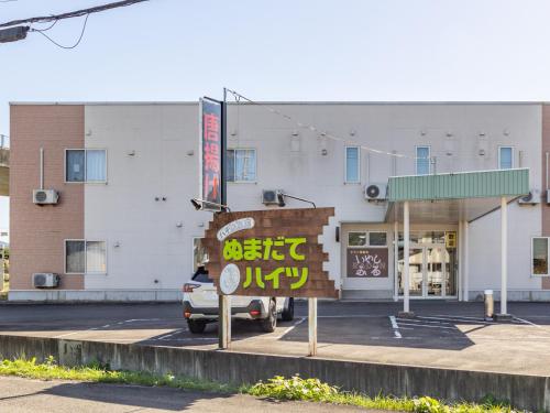 a sign in a parking lot in front of a building at Tabist Hachi no Oyado Numadate Heights in Odate