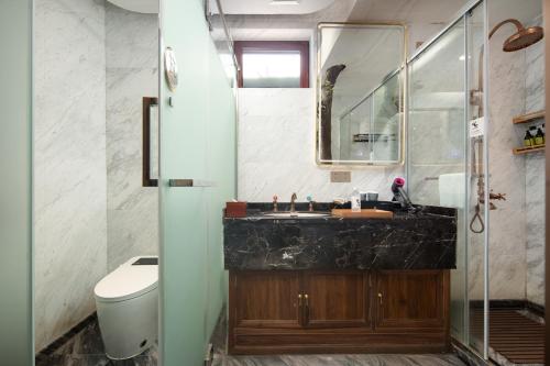 a bathroom with a sink and a toilet and a mirror at 三亚南山树屋隐世酒店 in Shangsimacun