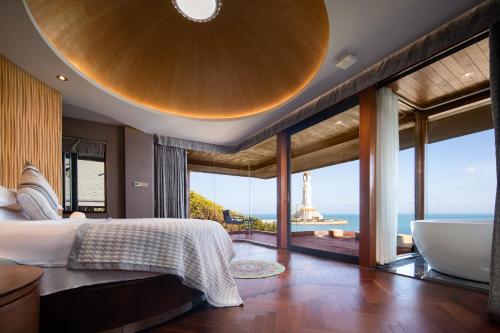 a bedroom with a large bed and a view of the ocean at 三亚南山树屋隐世酒店 in Shangsimacun