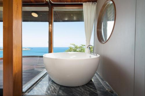 a bathroom with a large white tub in front of a window at 三亚南山树屋隐世酒店 in Shangsimacun