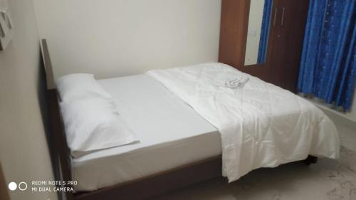 a bed in a room with white sheets and pillows at Dilmun Yercaud Villa in Yercaud