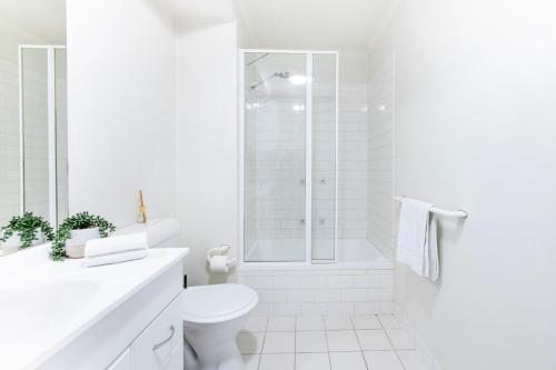 a white bathroom with a shower and a toilet at Stylish Cosy Gem w Pool, Tennis Court, & Parking in Melbourne