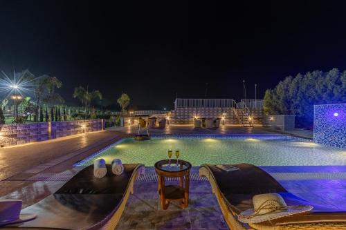 a swimming pool at night with a table and chairs at ELIVAAS 5 BHK With Pvt Pool & Garden - Zenora in Gurgaon