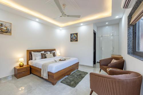 a bedroom with a bed and two chairs at ELIVAAS 5 BHK With Pvt Pool & Garden - Zenora in Gurgaon