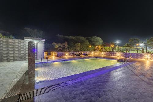 a swimming pool at night with lights at ELIVAAS 5 BHK With Pvt Pool & Garden - Zenora in Gurgaon