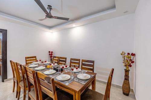 a dining room with a table with chairs and a ceiling fan at ELIVAAS 5 BHK With Pvt Pool & Garden - Zenora in Gurgaon