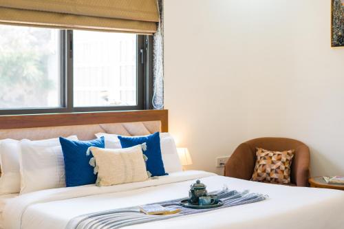 a bedroom with a bed with blue and white pillows at ELIVAAS 5 BHK With Pvt Pool & Garden - Zenora in Gurgaon
