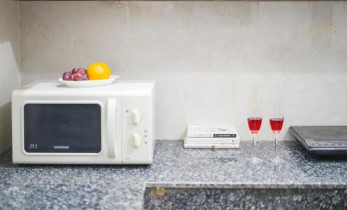 a microwave sitting on a counter with two glasses of wine at ELIVAAS 5 BHK With Pvt Pool & Garden - Zenora in Gurgaon