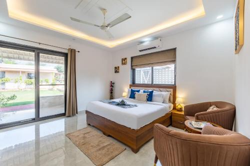 a bedroom with a bed and two chairs at ELIVAAS 5 BHK With Pvt Pool & Garden - Zenora in Gurgaon