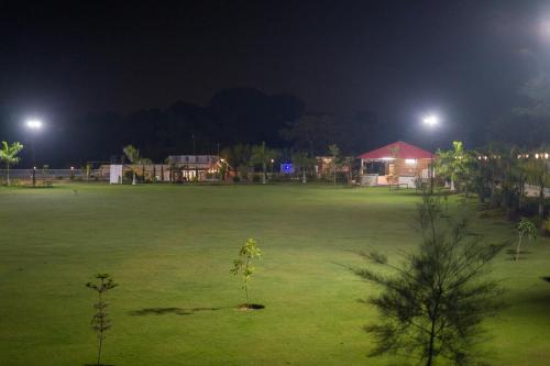 a large green field at night with lights at ELIVAAS 5 BHK With Pvt Pool & Garden - Zenora in Gurgaon