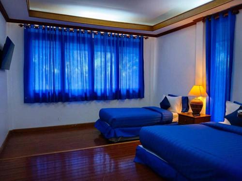 a bedroom with two beds and blue curtains at Samui Wooden Hill Resort in Lamai