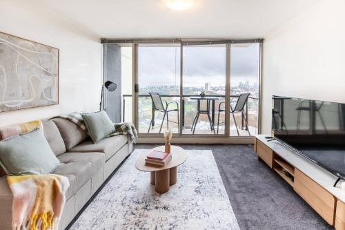 a living room with a couch and a tv and a table at Stylish Cosy Gem w Pool, Tennis Court, & Parking in Melbourne