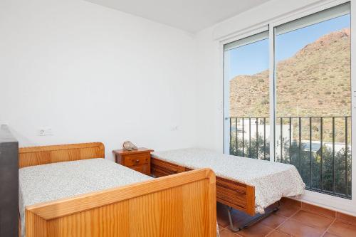 a bedroom with two beds and a large window at La Casa Del Volcán De Cabo De Gata in Las Hortichuelas Bajas