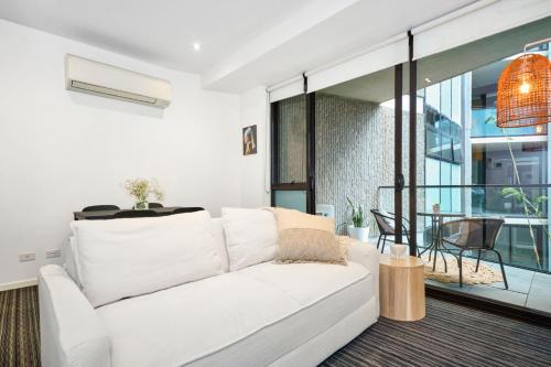 Il comprend un salon doté d'un canapé blanc et d'un balcon. dans l'établissement Stylish 1 Bedroom Retreat in St Kilda w Car Park, à Melbourne
