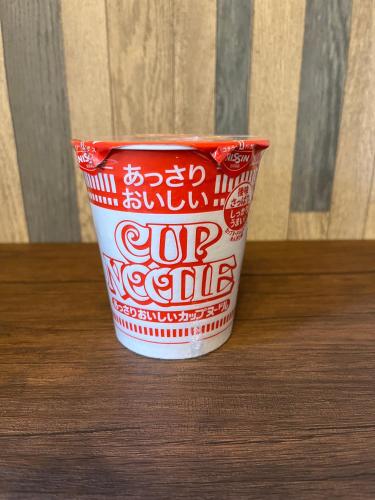 a red and white cup sitting on a table at Cycle Guest House SHIOKAZE in Setoda