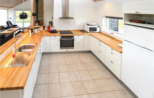 a kitchen with white cabinets and wooden counter tops at Holiday Home Pilemose in Skovby