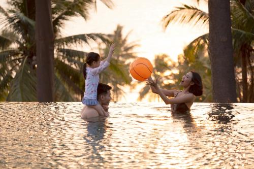 a woman and a child playing with a basketball in a swimming pool at Novus Jiva Anyer in Anyer