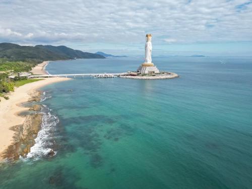 a lighthouse in the ocean next to a beach at 三亚南山树屋隐世酒店 in Shangsimacun