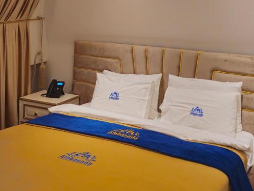a bed with blue and white pillows and a phone at Hotel Ambasada QTA in Patza-Kuqani