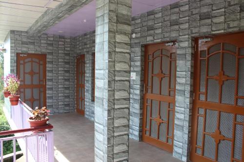 a front door of a house with a stone wall at Para Valley Home Stay in Bīr