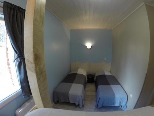 deux lits dans une petite pièce avec une fenêtre dans l'établissement Maison avec piscine couverte 8 chambres 22 personnes au coeur de la nature, à Saint-Sauveur-en-Rue